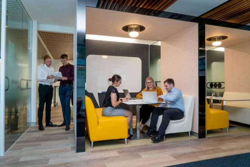 Employees in the hallway and booth talking in an office