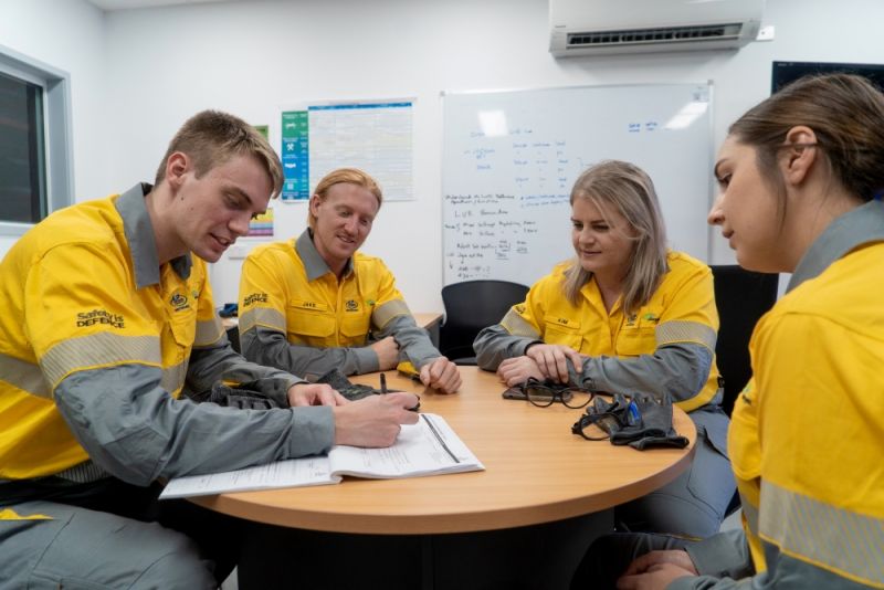 Apprentices sitting at a table completing office based training