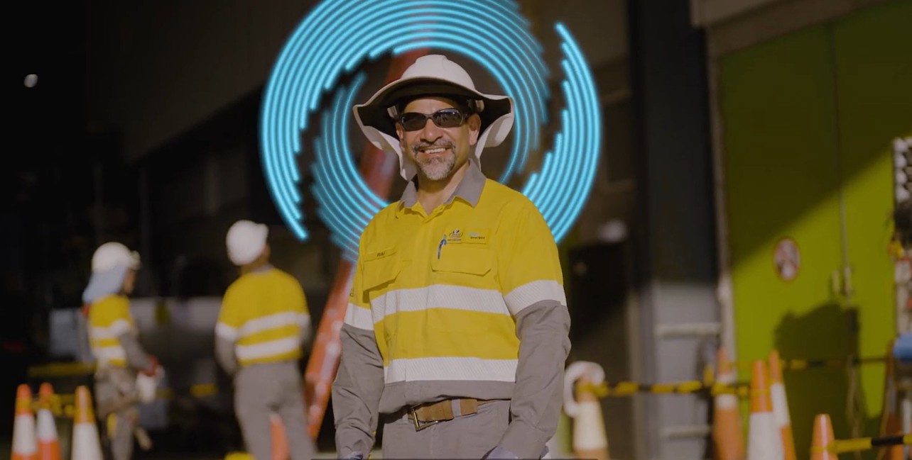 Worker standing out front of work building with workers in background