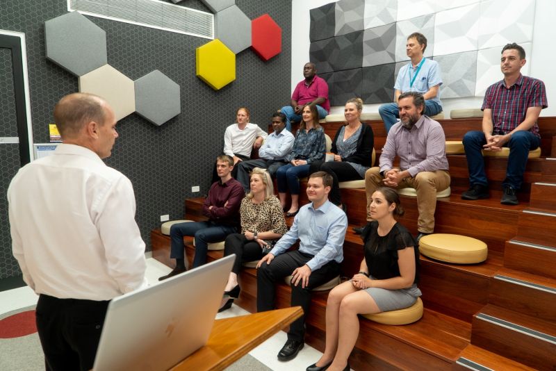 Group of employees sitting in atrium listening to a guest speaker